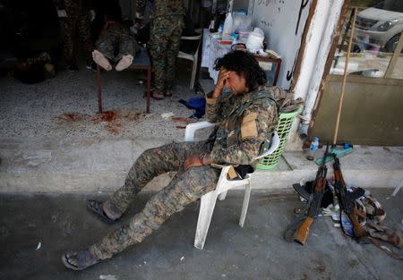 A Syrian Democratic Forces (SDF) fighter cries as medics treat his comrades injured by sniper fired by Islamic State militants in a field hospital in Raqqa, Syria June 28, 2017. REUTERS/Goran Tomasevic