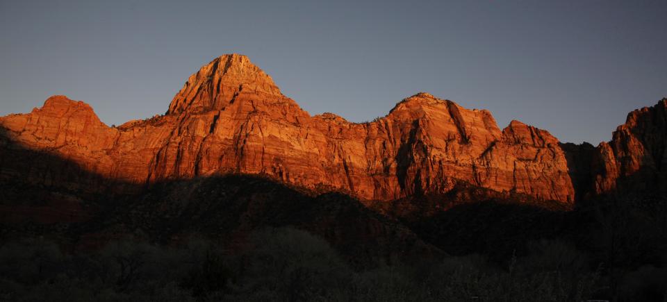 FILE - This Jan. 20, 2011 file photo shows shadows creeping up on sandstone cliffs glowing red as the sun sets on Zion National Park near Springdale, Utah. This is one of a number of scenic attractions, parks and other sites near enough to Las Vegas to add to itineraries as a day trip when visiting the gambling capital. (AP Photo/Julie Jacobson, file)