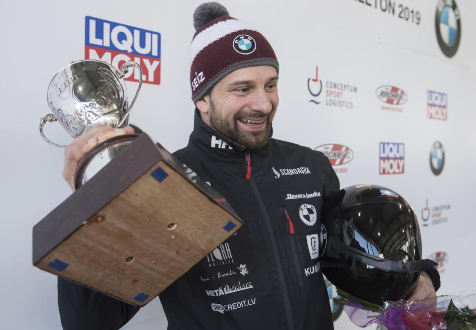 Martins Dukurs, of Latvia, holds up the trophy after winning the men's event at the Skeleton World Championships in Whistler, British Columbia, Friday March 8, 2019. (Darryl Dyck/The Canadian Press via AP)