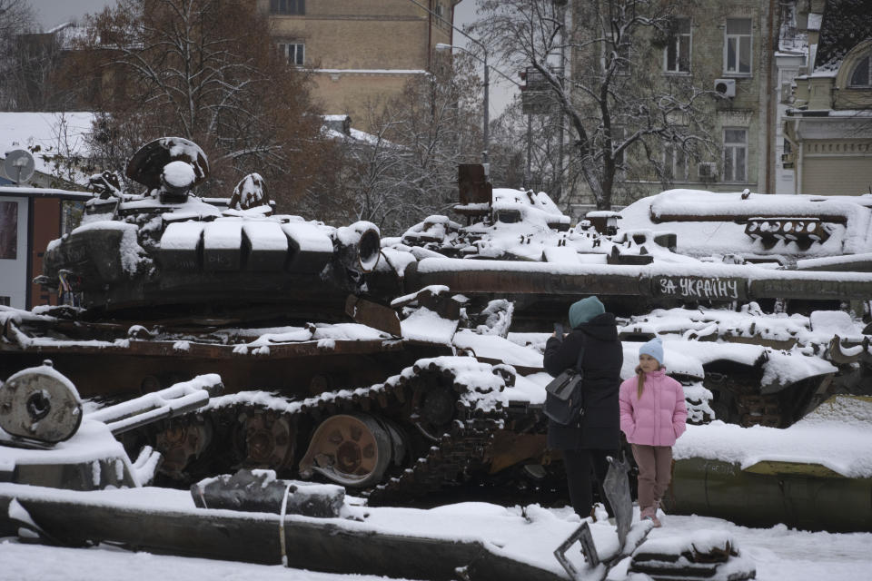 A woman and a child look at damaged Russian military vehicles in central Kyiv, Ukraine, Monday, Dec. 12, 2022. Ukraine has been fighting with the Russian invaders since Feb. 24 for over nine months. (AP Photo/Efrem Lukatsky)