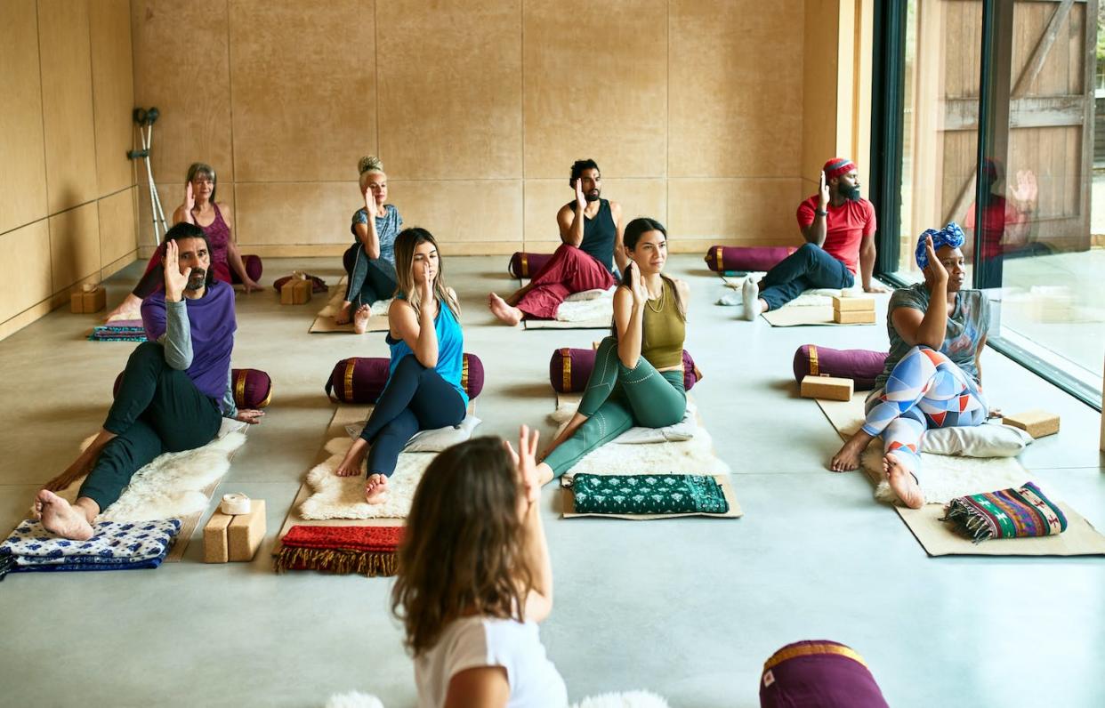 Yoga mixes physical exercise with meditation and breathing techniques. <a href="https://www.gettyimages.com/detail/photo/yoga-class-on-mats-in-studio-in-gentle-twist-royalty-free-image/1305098935?phrase=yoga%20group&adppopup=true" rel="nofollow noopener" target="_blank" data-ylk="slk:10,000 Hours/Digital Vision via Getty Images;elm:context_link;itc:0;sec:content-canvas" class="link ">10,000 Hours/Digital Vision via Getty Images</a>