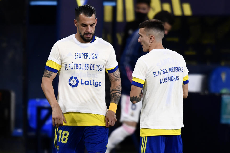 Álvaro Negredo (izquierda) y Salvi Sánchez, del Cádiz, visten camisetas con mensajes de protesta contra la Superliga europea, antes de su partido del miércoles 21 de abril de 2021, ante el Real Madrid (AP Foto/Jose Breton)