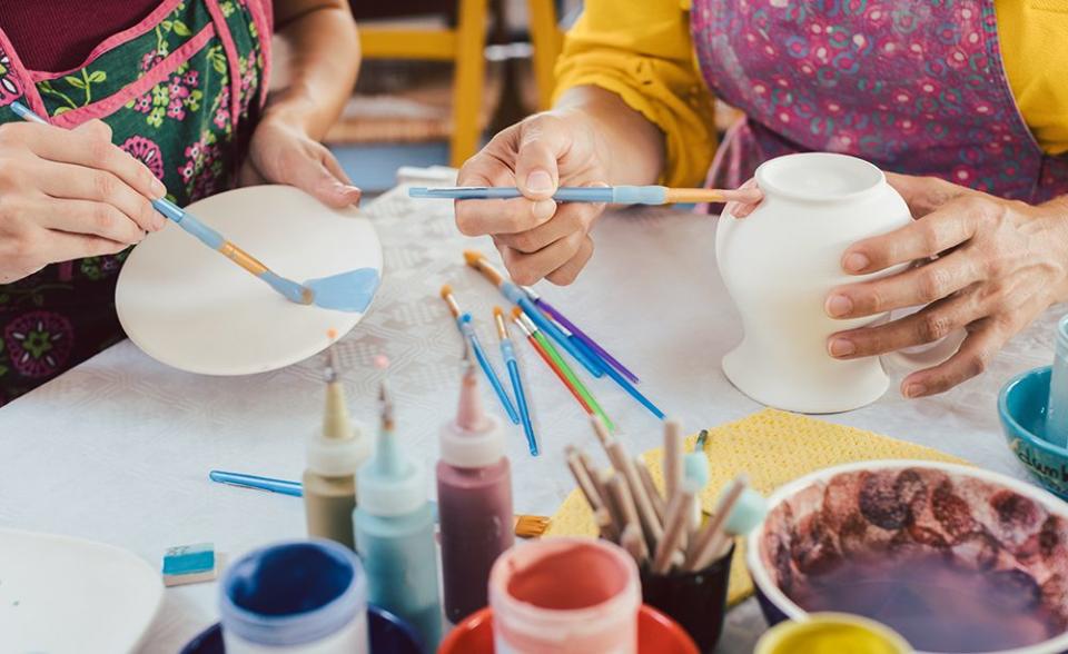 woman coloring handmade dishes using brush to paint color