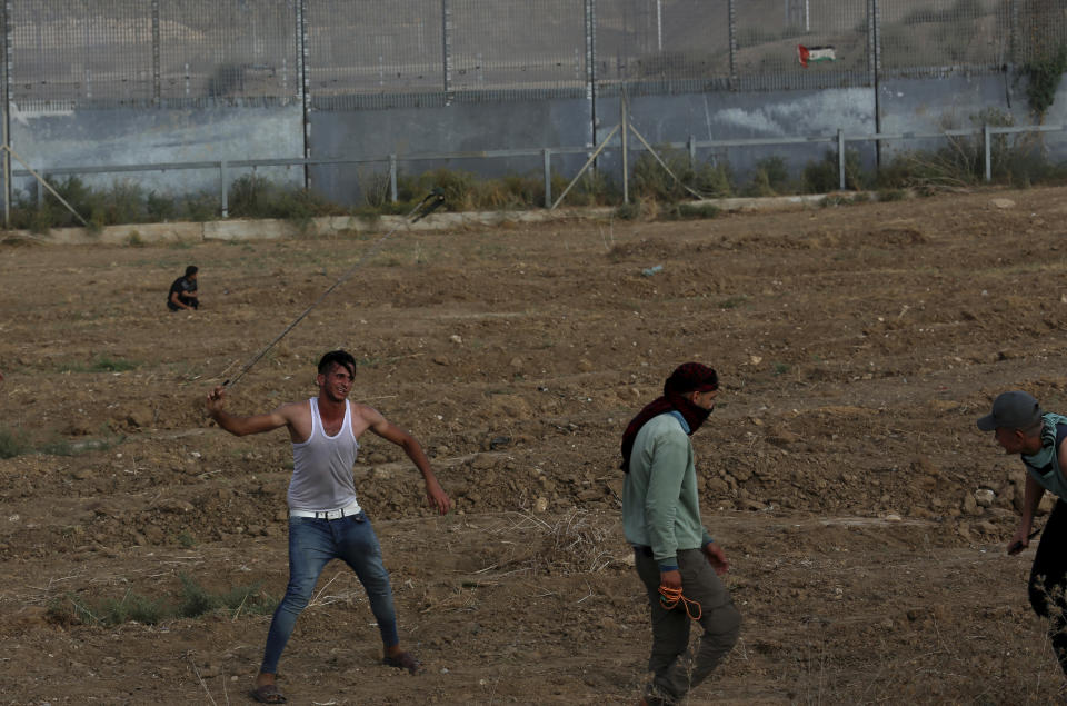 Protestors hurl stones at Israeli troops near the fence of Gaza Strip border with Israel, during a protest marking the anniversary of a 1969 arson attack at Jerusalem's Al-Aqsa mosque by an Australian tourist later found to be mentally ill, east of Gaza City, Saturday, Aug. 21, 2021. (AP Photo/Adel Hana)