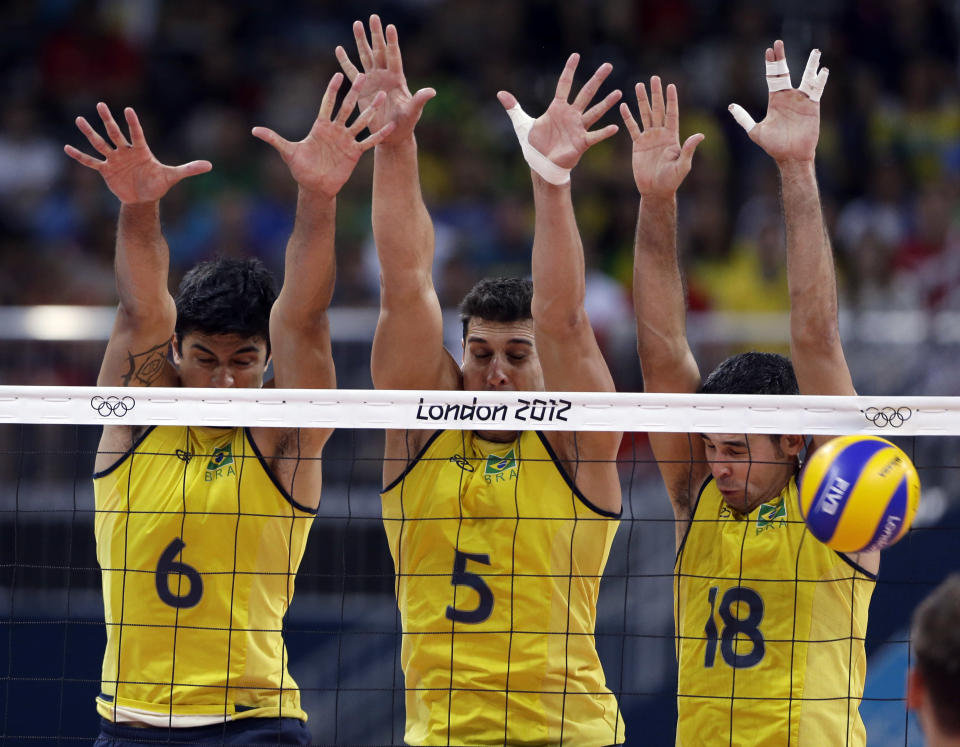 Brazil's Leandro Vissotto Neves, left, Sidnei dos Santos Jr., center, and Dante Amaral block a shot during a men's preliminary volleyball match against Serbia at the 2012 Summer Olympics, Saturday, Aug. 4, 2012, in London. (AP Photo/Jeff Roberson)