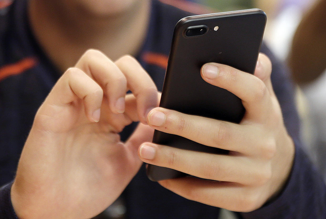 FILE - In this Sept. 16, 2017, file photo, a person uses a smart phone in Chicago. For many of us, a smartphone addiction is not so much a debilitating disease but a constant, nagging inconvenience we can’t seem to shake. But it’s not all our fault. From the constant notifications to the color schemes to the "likes," followers and in-game rewards out phones and the apps on them were created so we’ll use them as much as possible. But there are ways to fight back. (AP Photo, File)