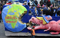 <p>A carnival float depicts a dinosaur with the U.S. flag on its hat eating a large chunk from the earth during the traditional Rose Monday parade in Duesseldorf, Germany, Shrove, Feb. 12, 2018. (Photo: Martin Meissner/AP) </p>