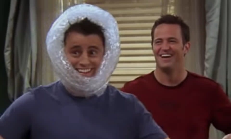 Joey with bubble wrap on his head and Chandler behind him in "Friends"