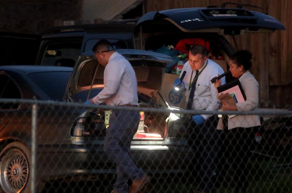 Three law officers holding flashlights outside a residence