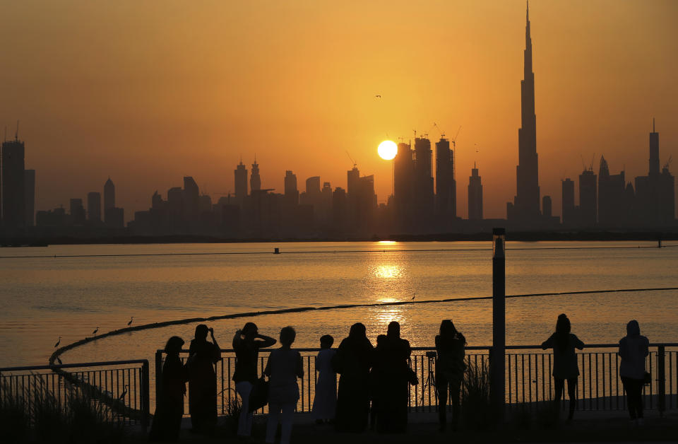 In this Oct. 7, 2016 file photo, people watch the sunset over the skyline, with Burj Khalifa at right, in Dubai, United Arab Emirates. The United Arab Emirates announced on Saturday a major overhaul of the country’s Islamic personal laws, allowing unmarried couples to cohabitate, loosening alcohol restrictions and criminalizing so-called “honor killings.” (AP Photo/Kamran Jebreili, File)