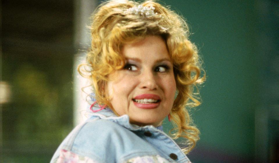 Paulette with curly hair tied half up and wearing a jean jacket, looking surprised