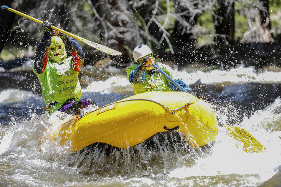 Calen Golas, left, and Jordan Beckman man a Mini Max raft down the Gore Creek wearing masks in protest of Secretary of the Interior David Bernhardt, who is speaking at the Western Governors' Association Monday, June 10, 2019 in Vail, Colo. The protest also took place on land on the recreation path along the river as the Sierra Club organized the rally. (Chris Dillmann/Vail Daily via AP)