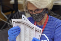 FILE - In this Tuesday, Sept. 14, 2021, file photo, an election worker inspects a ballot for damage before they are sent to be tabulated at the Sacramento County Registrar of Voters Office in Sacramento, Calif. On Friday, Sept. 17, 2021, The Associated Press reported on stories circulating online incorrectly asserting there was fraud in California’s recall election because voters were given Sharpie pens or other permanent markers, which the false posts said is illegal and will invalidate ballots. “Sharpie pens are safe and reliable to use on ballots, and recommended due to their quick-drying ink,” reads a Nov. 5 statement from Dominion Voting Systems. “Regarding potential ink bleed-through, Dominion’s systems never allow for the creation of ballots with overlapping vote bubbles between the front and back pages of a ballot.” (AP Photo/Rich Pedroncelli, File)