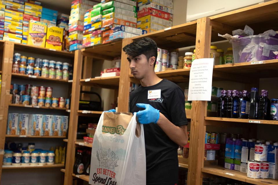 Volunteers Eshaan Doegar carries a bag he packed with donations into the cart at Warminster Food Bank in Warminster on Friday, July 15, 2022.