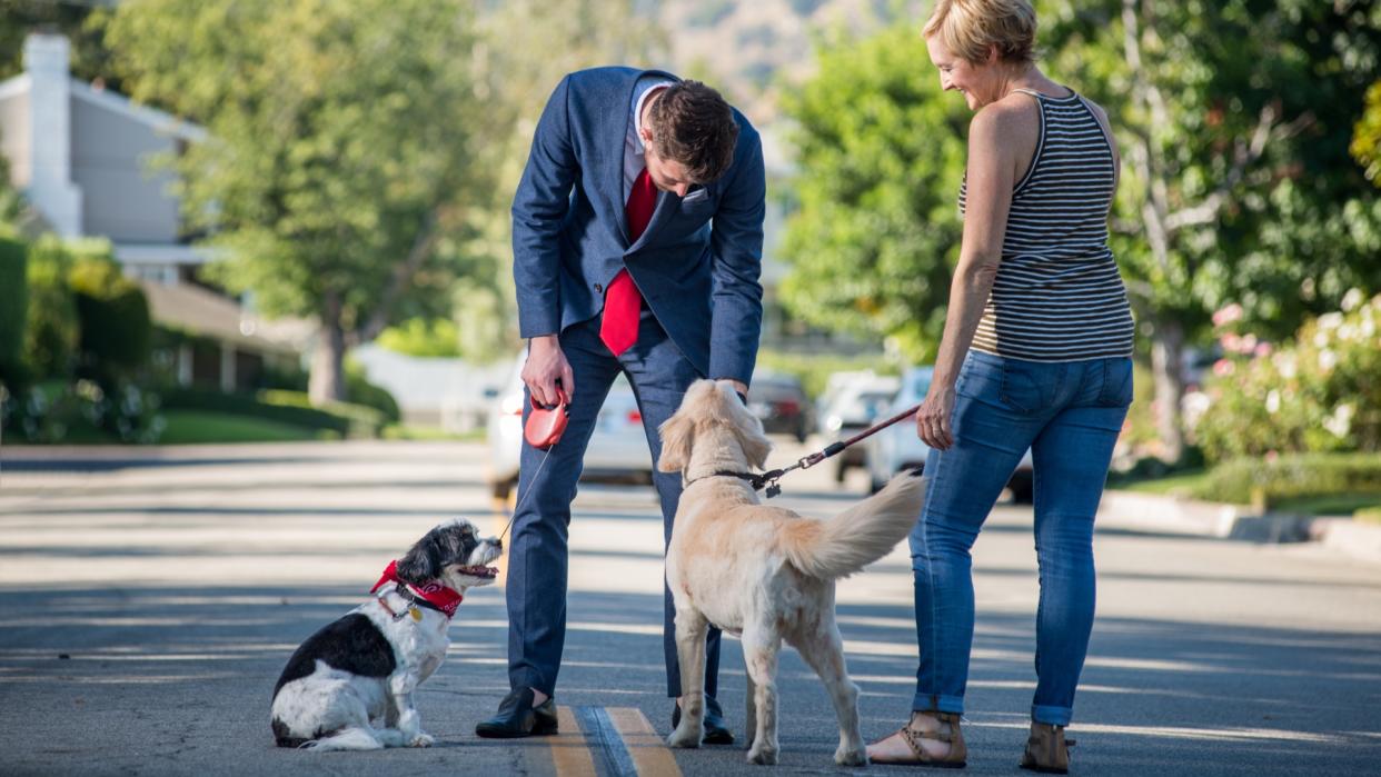  Man stopping to pet woman's dog. 