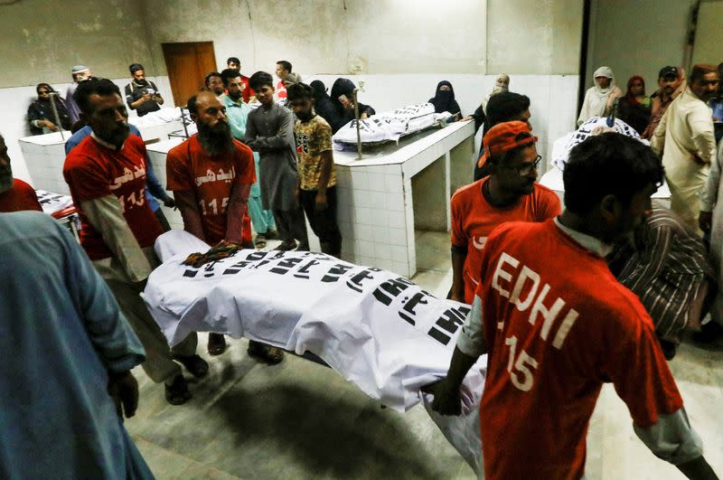 People mourn the death of a relative, who was killed with others in a stampede during handout distribution, in Karachi