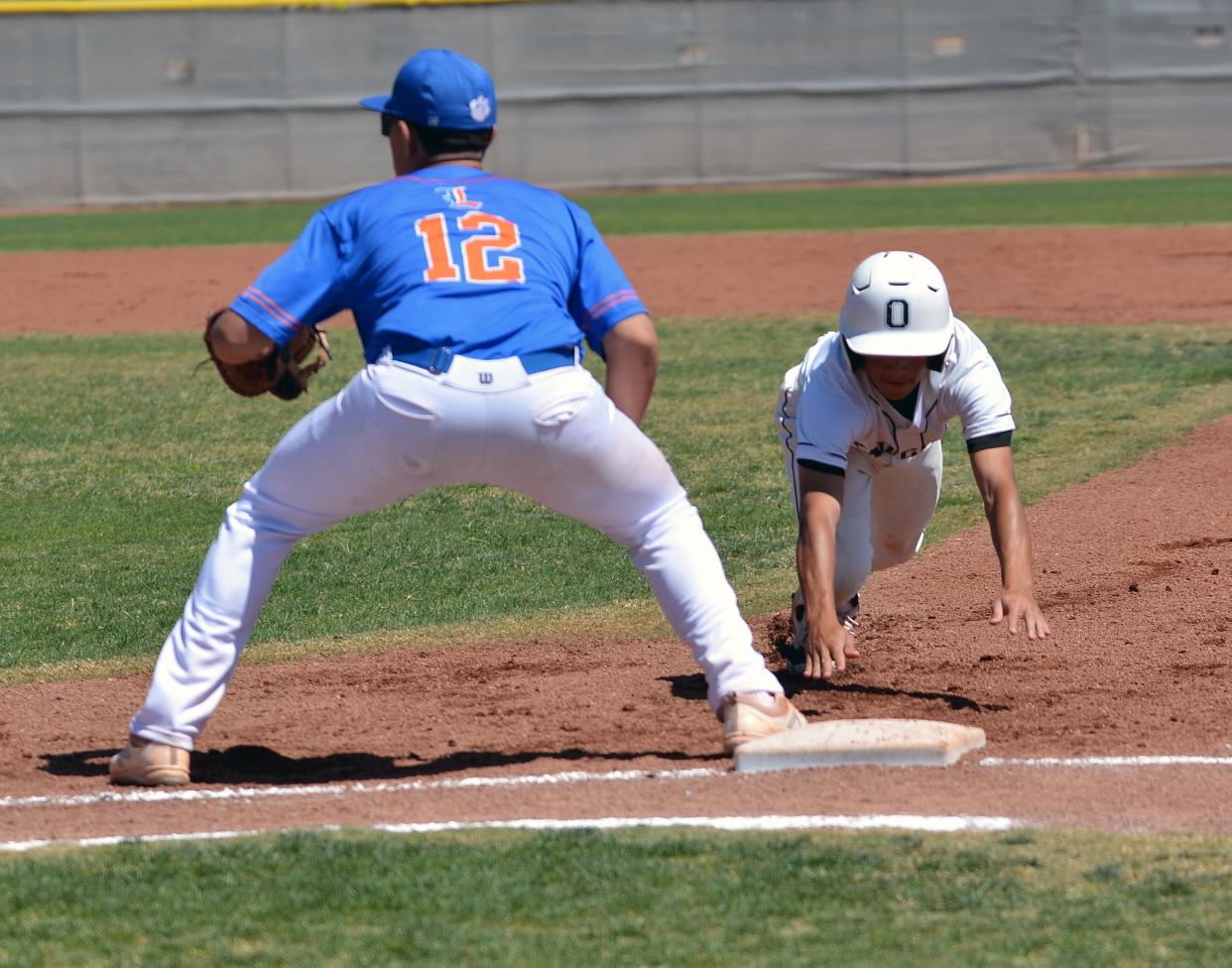 Knight Tyce McPhearson (right) dives back to first base as Organ Mountain faced Los Lunas High in first round baseball playoff action on Saturday.  Photo taken 5/7/22.