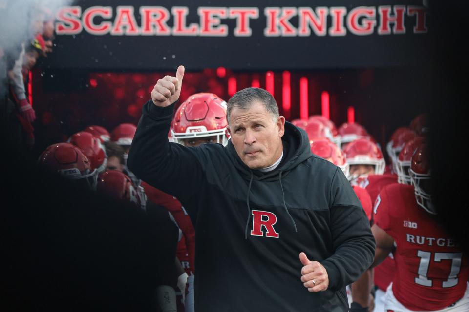 Rutgers head coach Greg Schiano runs out to the field with his team in November.