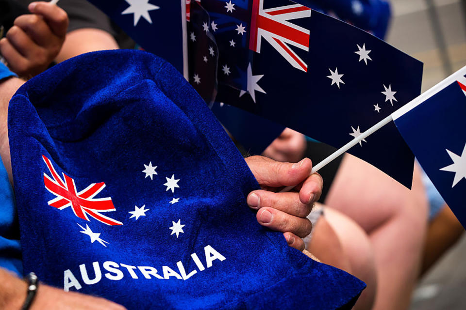 People wave flags and festive merchandise to celebrate Australia Day.
