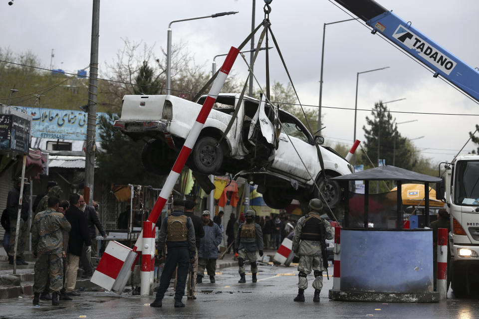 A damaged vehicle is removed from the site of a bomb explosion in Kabul, Afghanistan, Monday, March 30, 2020. A sticky bomb attached to the vehicle detonated, according to Firdaus Faramraz, spokesman for the Kabul police chief. (AP Photo/Rahmat Gul)