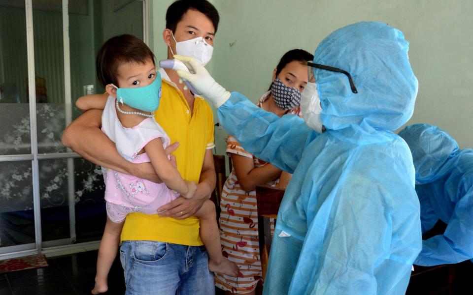 A health worker gets the temperature of residents at the area of a newly found coronavirus infected patient in Da Nang city - REUTERS