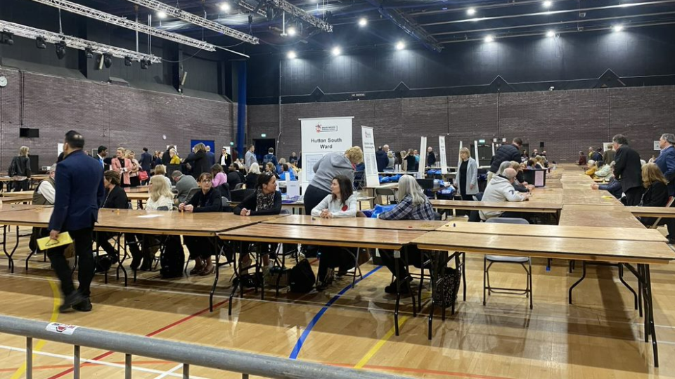 People sit at tables waiting to count votes