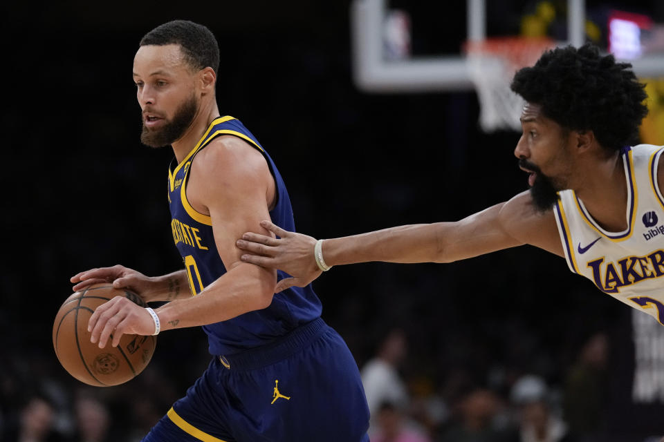 Los Angeles Lakers guard Spencer Dinwiddie, right, defends against Golden State Warriors guard Stephen Curry during the first half of an NBA basketball game in Los Angeles, Saturday, March 16, 2024. (AP Photo/Ashley Landis)