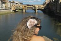 Ponte Vecchio Bridge, Florence, Italy: A young woman with a flower in her hair stands across from the Ponte Vecchio bridge over the Arno river in Florence, Italy.