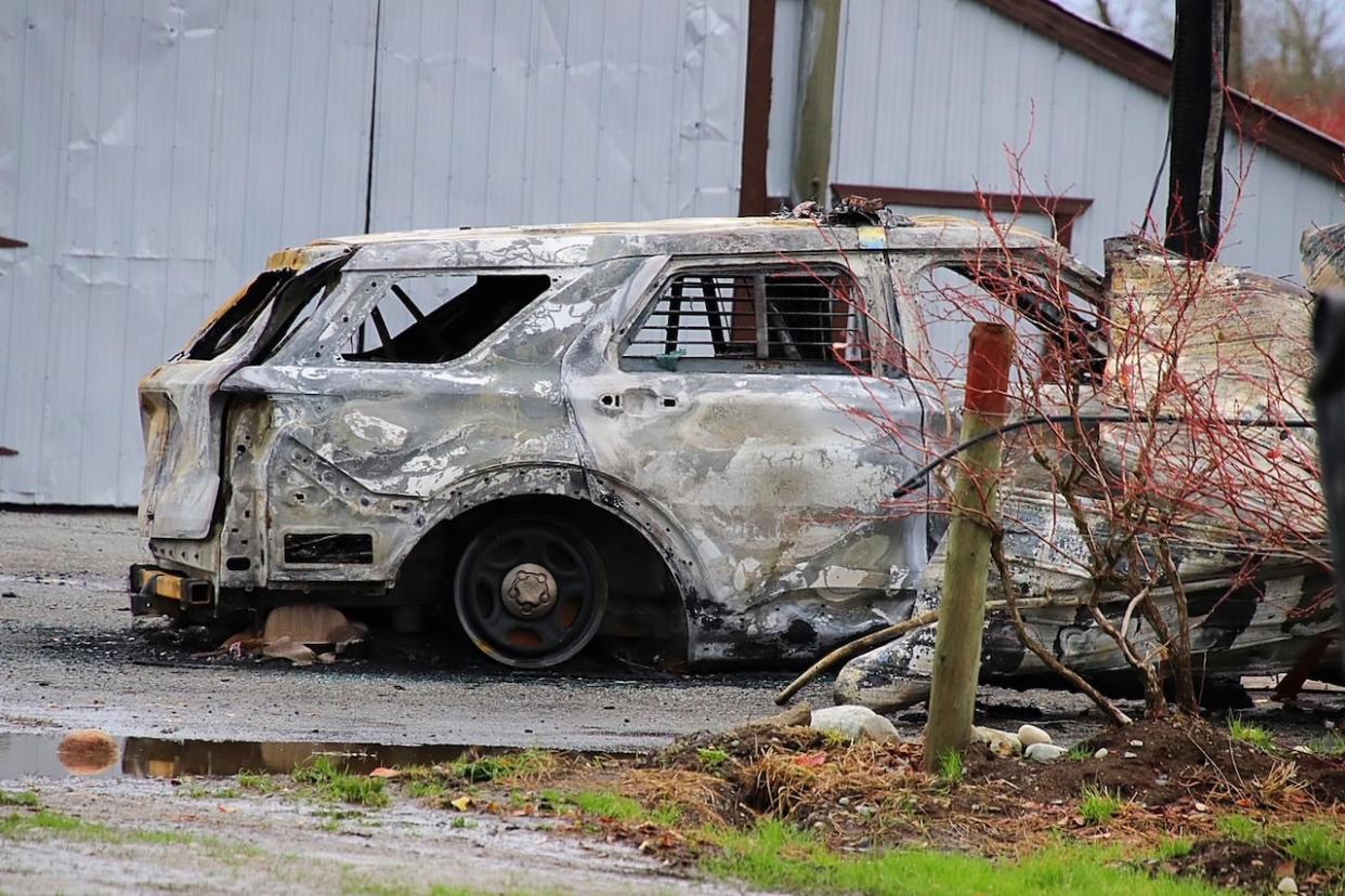 The remains of a torched police vehicle on a property on the 23500 block of 0 Avenue in Langley, B.C., near the U.S. border the day after a large police operation in the area. (Shane MacKichan - image credit)