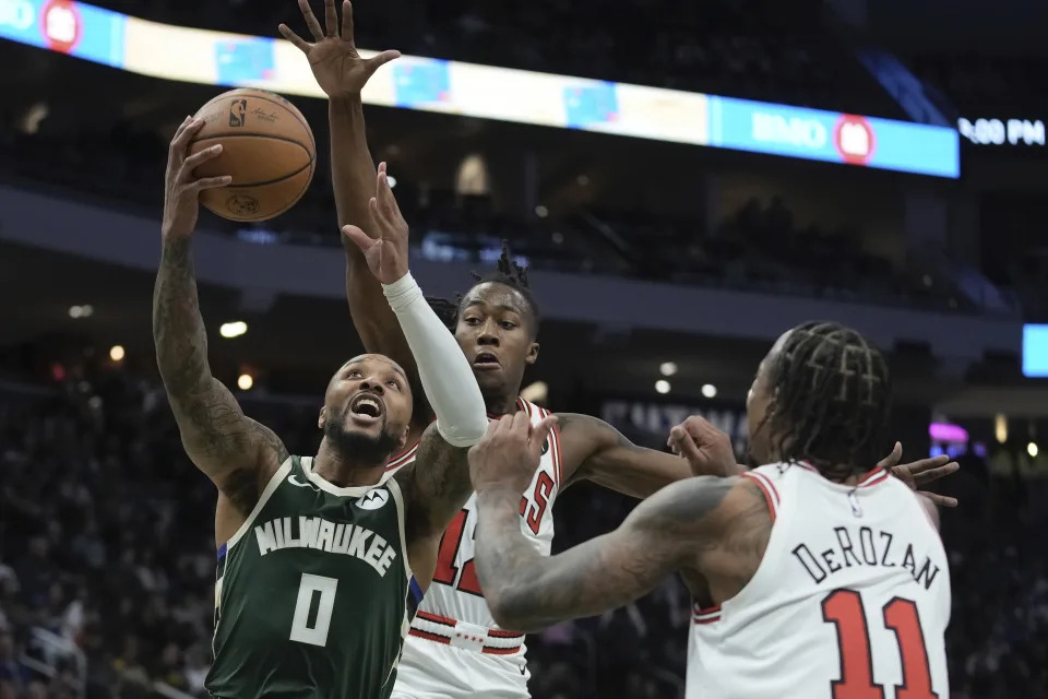 Milwaukee Bucks' Damian Lillard shoots past Chicago Bulls' Ayo Dosunmu DeMar DeRozan during the first half of an NBA basketball game Monday, Dec. 11, 2023, in Milwaukee. (AP Photo/Morry Gash)