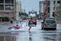 <p>People make their way down partially flooded roads following the passage of Hurricane Harvey on Aug. 26, 2017 in Galveston, Texas. (Photo: Brendan Smialowski/AFP/Getty Images) </p>