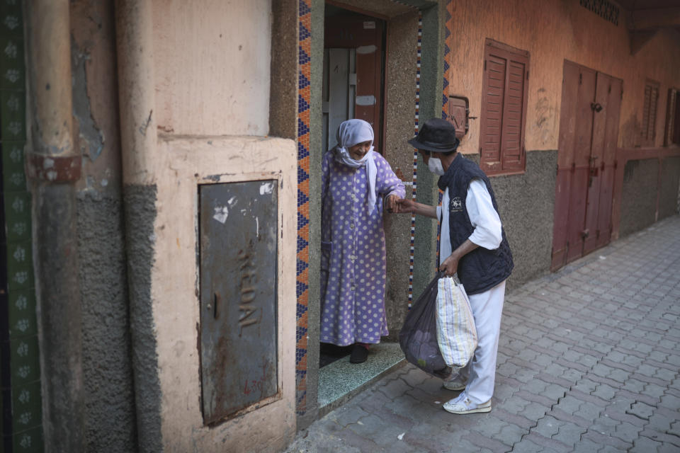 Belhussein Abdelsalam, a Charlie Chaplin impersonator greets his mother outside his home after a day of working, in Sale, near Rabat, Morocco, Tuesday, March 23, 2021. When 58-year-old Moroccan Belhussein Abdelsalam was arrested and lost his job three decades ago, he saw Charlie Chaplin on television and in that moment decided upon a new career: impersonating the British actor and silent movie maker remembered for his Little Tramp character. (AP Photo/Mosa'ab Elshamy)