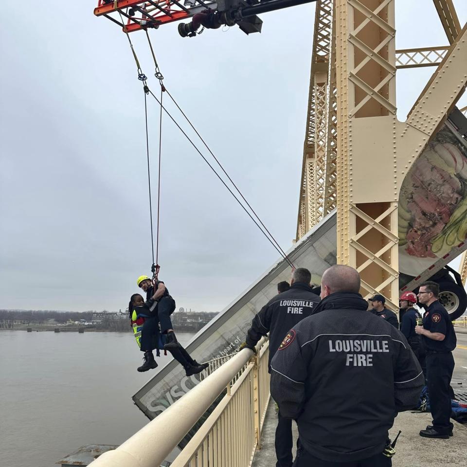 This photo provided by Louisville Division of Fire, Louisville Fire Dept. Louisville firefighter Bryce Carden rescues the driver of semitruck that is dangling off the Clark Memorial Bridge over the Ohio River on Friday, March 1, 2024 in Louisville, Ky. The driver was pulled to safety by firefighters following the three-vehicle crash on the bridge connecting Louisville, Kentucky to southern Indiana(Louisville Division of Fire via AP)