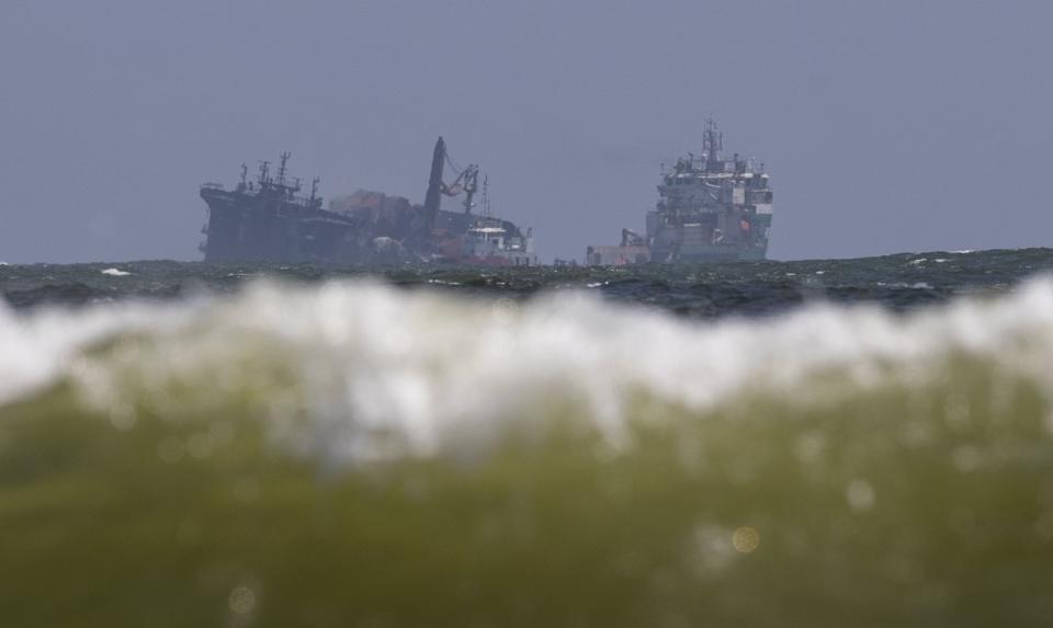 The MV X-Press Pearl, left, is pulled by a navel vessel at Kapungoda, where it is anchored off Colombo port on the outskirts of Colombo, Sri Lanka, Wednesday, June 2, 2021. Salvage experts were attempting to tow the fire-stricken container ship that had been loaded with chemicals into the deep sea as the vessel started to sink Wednesday off Sri Lanka's main port, officials said. Water submerged the MV X-Press Pearl's quarterdeck a day after firefighters extinguished a blaze that had been burning for 12 days. (AP Photo/Eranga Jayawardena)