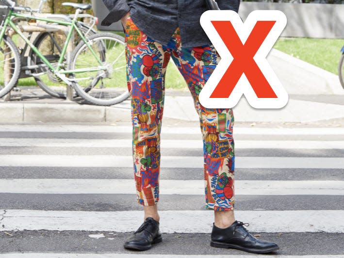 red x over person crossing a street wearing brightly colored patterned pants and a gray shirt