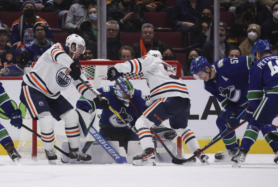 Vancouver Canucks goalie Spencer Martin, second left, stops Edmonton Oilers' Connor McDavid, left, and Kailer Yamamoto, center, as Vancouver's Tyler Myers (57) defends during the second period of an NHL hockey game, Tuesday, Jan. 25, 2022 in Vancouver, British Columbia. (Darryl Dyck/The Canadian Press via AP)