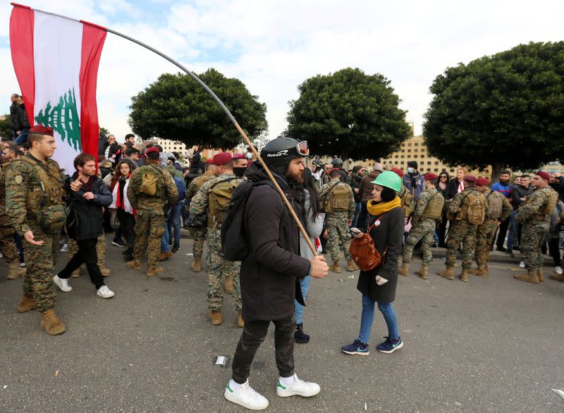 A demonstrator holds the Lebanese flag during a protest seeking to prevent MPs and government officials from reaching the parliament for a vote of confidence, in Beirut