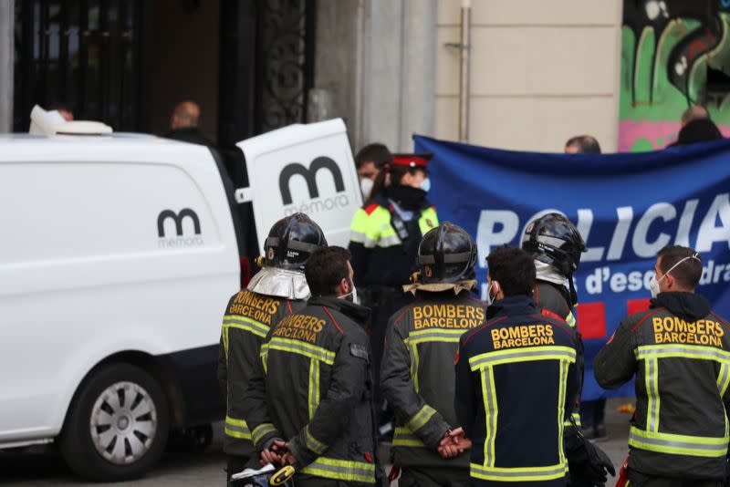 Firefighters and police stand in front of a burned building in Barcelona