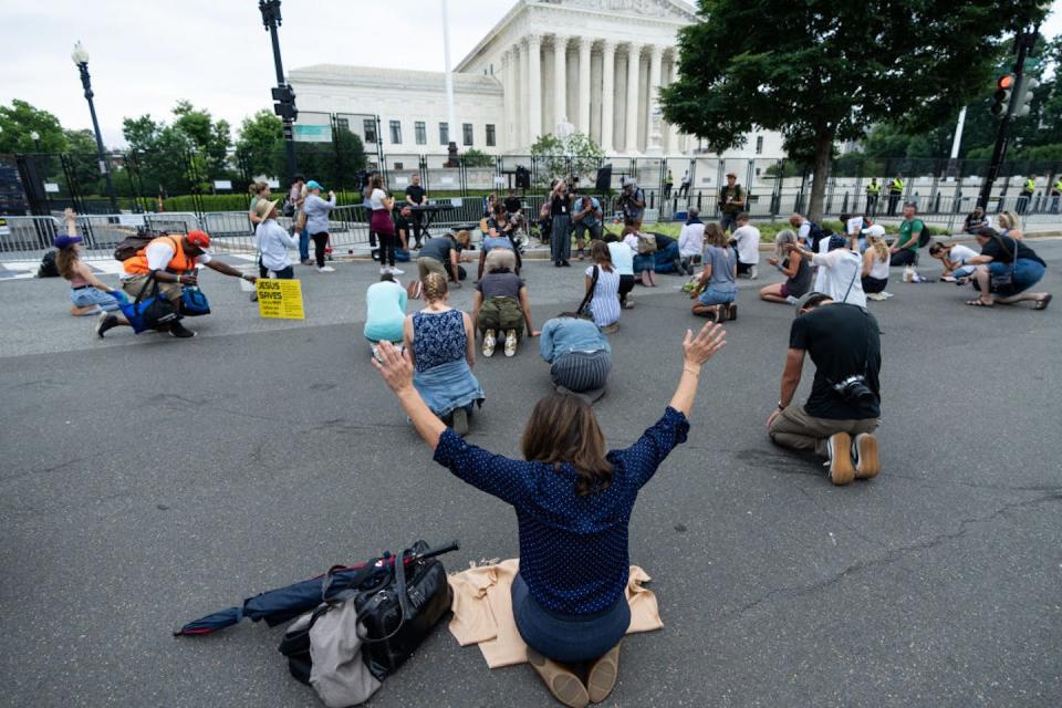 People kneel and pray as Christian singer-songwriter Sean Feucht performs outside the U.S. Supreme Court after the Kennedy v. Bremerton ruling on June 27, 2022. <a href="https://www.gettyimages.com/detail/news-photo/people-kneel-and-pray-as-christian-singer-songwriter-sean-news-photo/1241572598?adppopup=true" rel="nofollow noopener" target="_blank" data-ylk="slk:Bill Clark/CQ-Roll Call, Inc via Getty Images;elm:context_link;itc:0;sec:content-canvas" class="link ">Bill Clark/CQ-Roll Call, Inc via Getty Images</a>