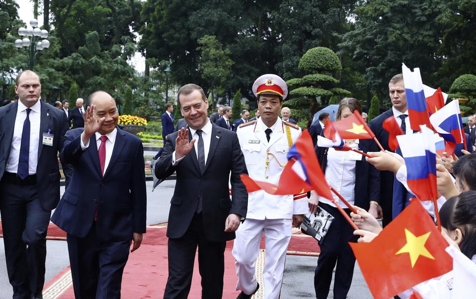 Russian Prime Minister Dmitry Medvedev, right, and his Vietnamese counterpart Nguyen Xuan Phuc, wave school children before heading for talks behind closed doors in Hanoi, Vietnam, Monday, Nov. 19, 2018. Medvedev is in Vietnam for a two-day visit to boost ties between the two countries. (Hoang Thong Nhat/ Vietnam News Agency via AP)