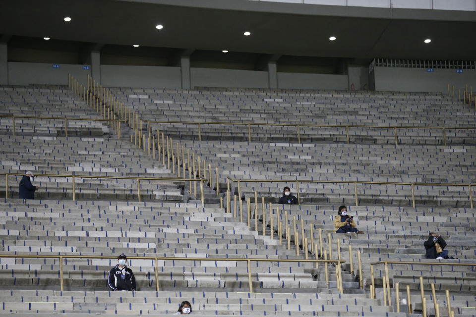 Unos cuantos trabajadores y dirigentes acreditados se sientan en el graderío del Estadio Olímpico Universitario de la Ciudad de México, antes del partido de ida de la final entre Pumas y León, el jueves 10 de octubre de 2020 (AP Foto/Rebecca Blackwell)