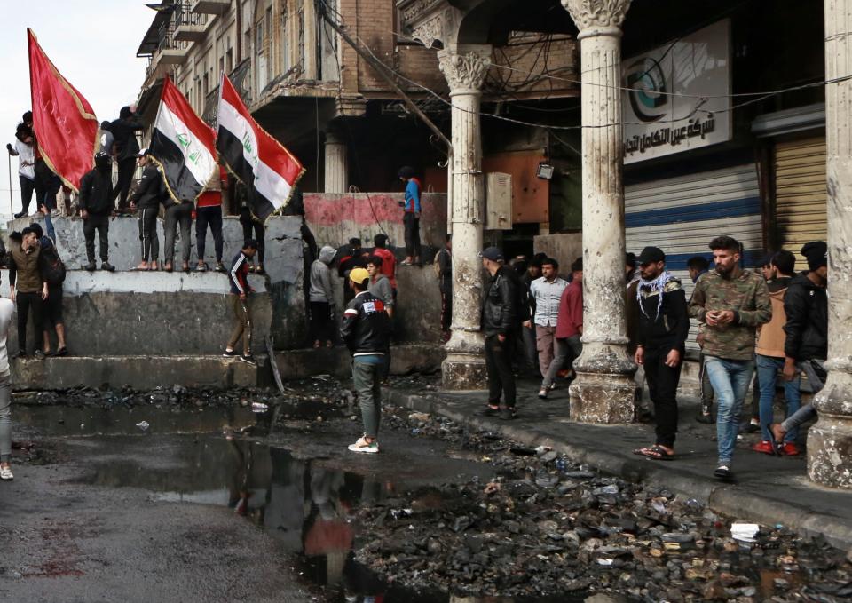 Anti-government protesters gather near barriers set up by security forces to close Rasheed Street during ongoing protests in Baghdad, Iraq, Tuesday, Dec. 3, 2019. At least 400 people have died since the leaderless uprising shook Iraq on Oct. 1, with thousands of Iraqis taking to the streets in Baghdad and the predominantly Shiite southern Iraq decrying corruption, poor services, lack of jobs and calling for an end to the political system that was imposed after the 2003 U.S. invasion. (AP Photo/Khalid Mohammed)