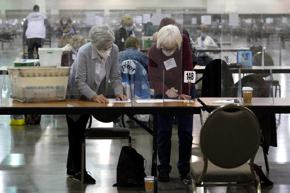 Election officials check ballots during a Milwaukee hand recount of Presidential votes at the Wisconsin Center, Friday, Nov. 20, 2020, in Milwaukee, Wis. The recount of the presidential election in Wisconsin's two most heavily Democratic counties began Friday with President Donald Trump's campaign seeking to discard tens of thousands of absentee ballots that it alleged should not have been counted. (AP Photo/Nam Y. Huh)