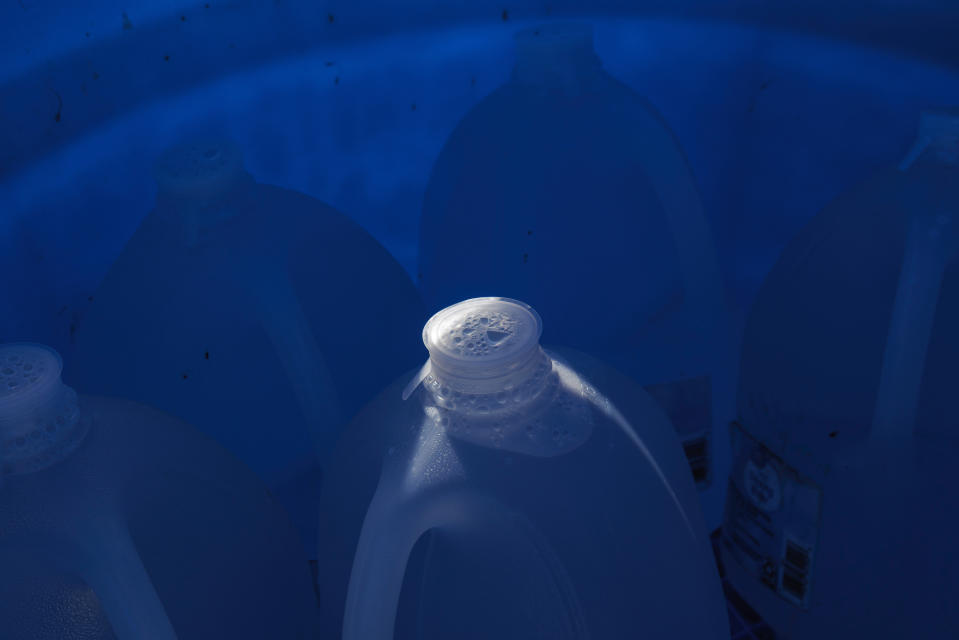 Sealed jugs of fresh water sit inside a water station for immigrants along a fence line near a roadway in rural Jim Hogg County, Texas, Tuesday, July 25, 2023. The South Texas Human Rights Center maintains over 100 blue barrels consistently stocked with water across rural South Texas to serve as a life-saving measure in the sweltering heat for immigrants who have crossed into the United States to travel north. (AP Photo/Michael Gonzalez)