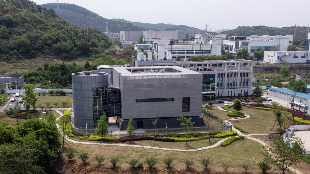 An aerial view of clusters of large buildings on landscaped grounds surrounded by mountains.