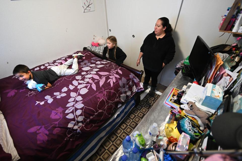 A women with two small children stands in a cramped room