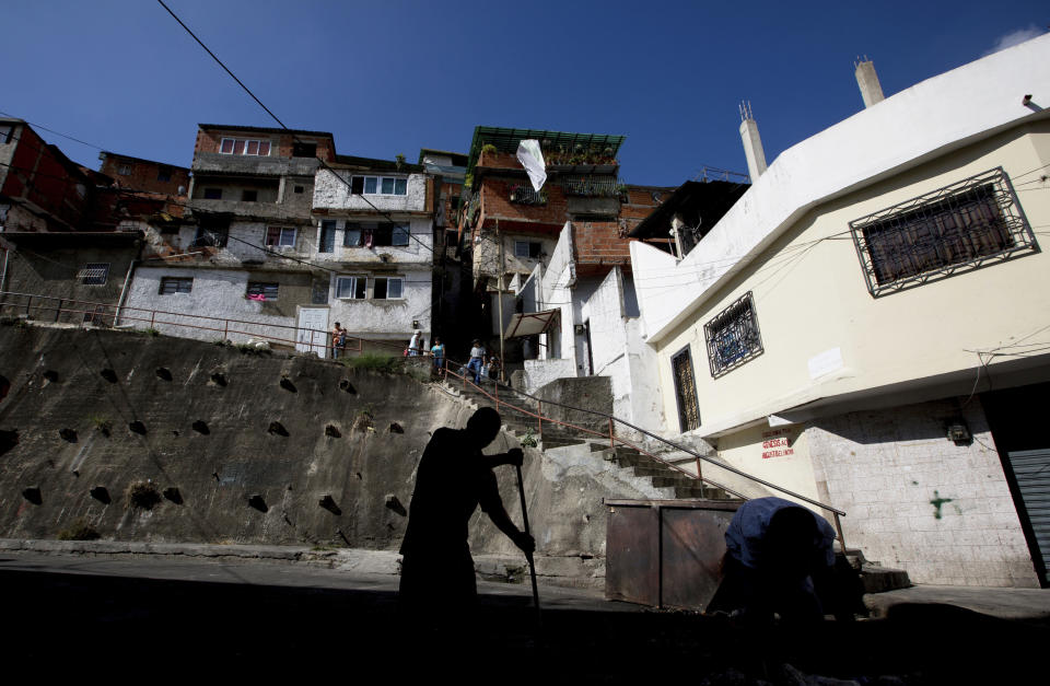 A resident of the Cotiza neighborhood sweeps a street a day after isolated protests in response to the arrest of National Guardsmen who mounted an uprising against President Nicolas Maduro, in Caracas, Venezuela, Tuesday, Jan. 22, 2019. Working class neighborhoods in Venezuela's capital sifted through charred rubble and smoldering trash on Tuesday, after violence erupted in the streets a day prior. (AP Photo/Fernando Llano)