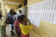 Voters search for their names before casting their votes in the presidential election in Lome, Togo, Saturday, Feb. 22, 2020. The West African nation of Togo is voting Saturday in a presidential election that is likely to see the incumbent re-elected for a fourth term despite years of calls by the opposition for new leadership. (AP Photo/Sunday Alamba)