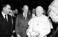 Pope John Paul II holds a ball to be used in the World Cup Soccer opening game as FIFA President Joao Havelange looks on in Rome December 9, 1989. REUTERS/File photo