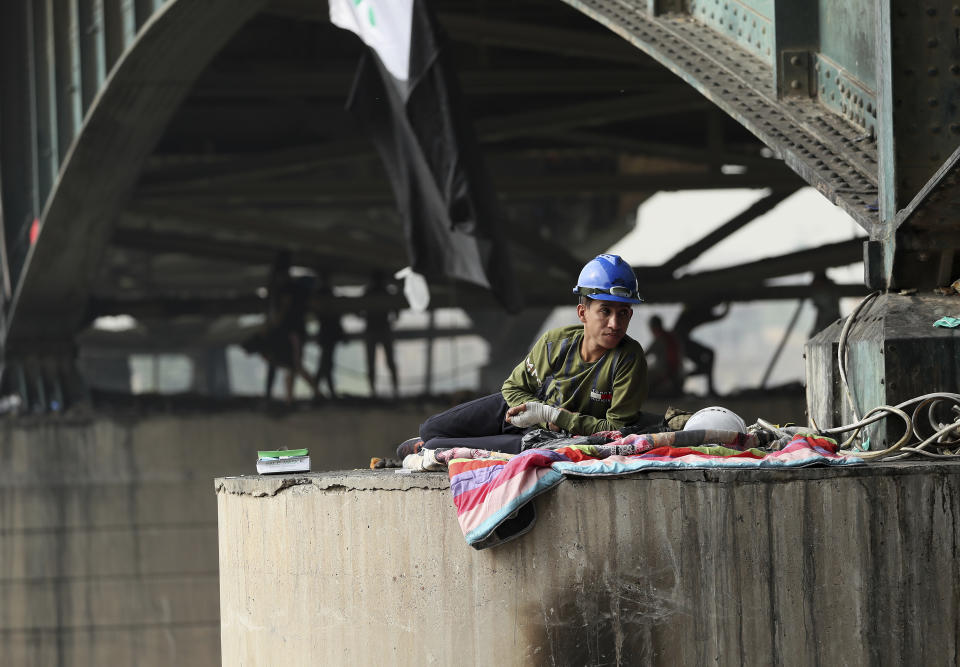 A protesters rest under the Joumhouriya Bridge, that leads to the Green Zone where many government offices and embassies are located, during ongoing anti-government protests, in Baghdad, Iraq, Sunday, Nov. 3, 2019. (AP Photo/Hadi Mizban)